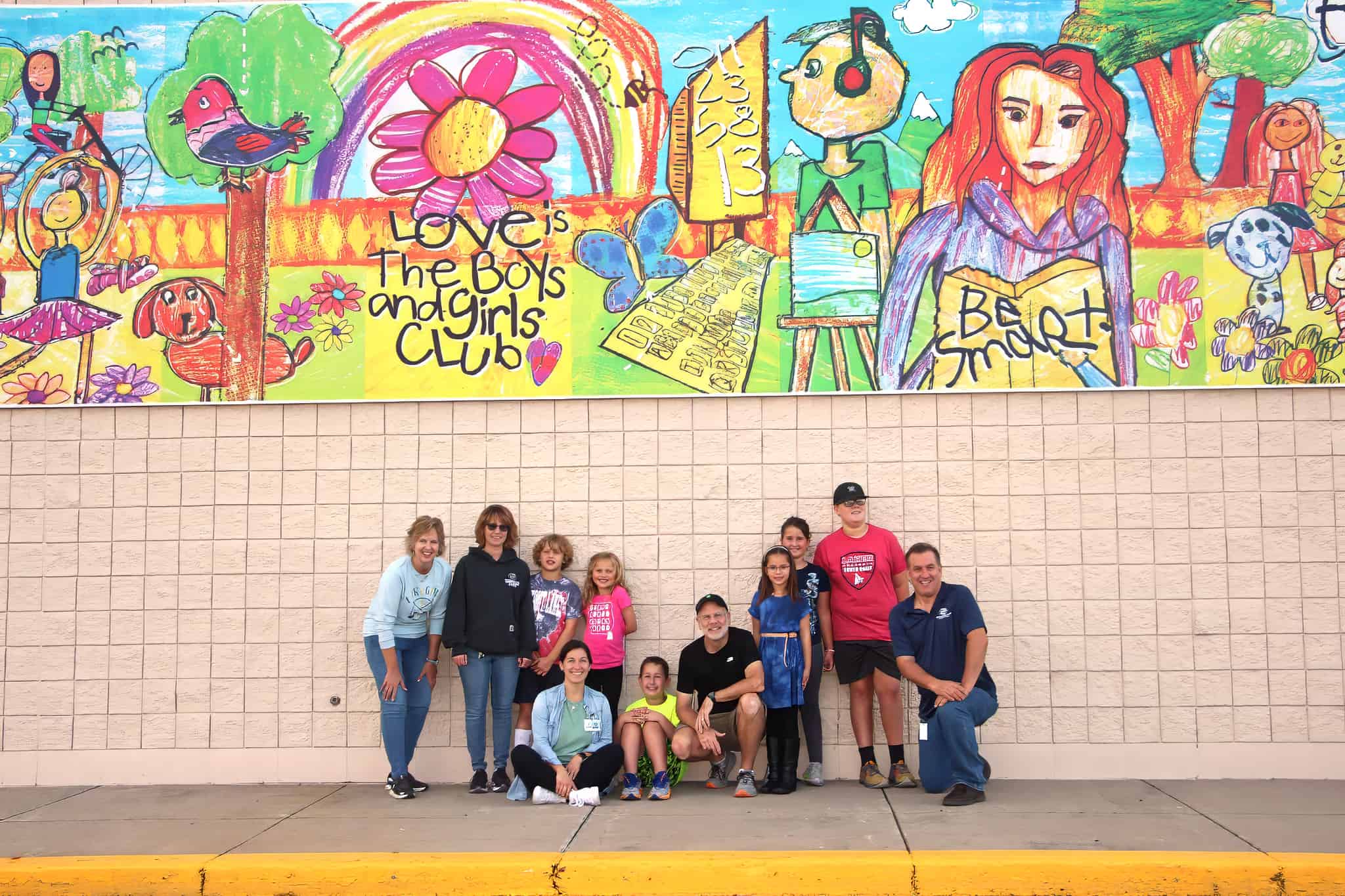 "Love is the Boys & Girls Club" mural • Project 412, Boys & Girls Club Thrift Store & MORE store, and Boys & Girls Club leaders and youth standing in front of a segment of the art • on the exterior wall of the Boy & Girls Club Thrift Store & MORE • Artist: Paul Johnson