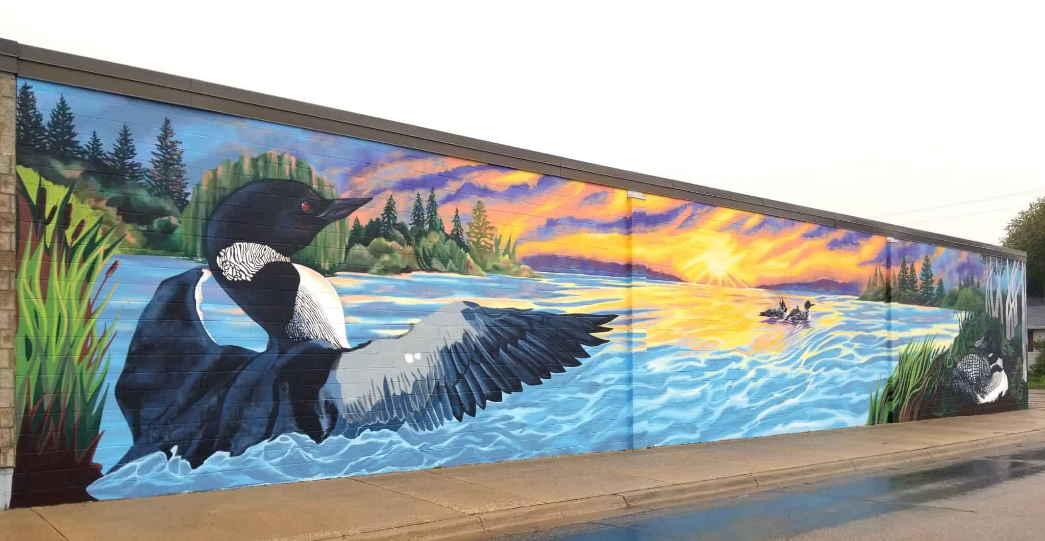 "The Dream" mural on the wall of Noah's Home Furnishings • the sunset and loon scene • Artist: Aryn Lill
