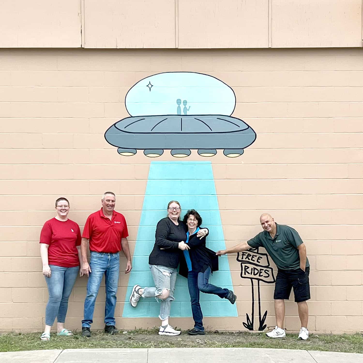 Precision Printing of MN staff standing in front of the "Free Rides" UFO mural • Precision Printing building • Artist: Hannah Spry